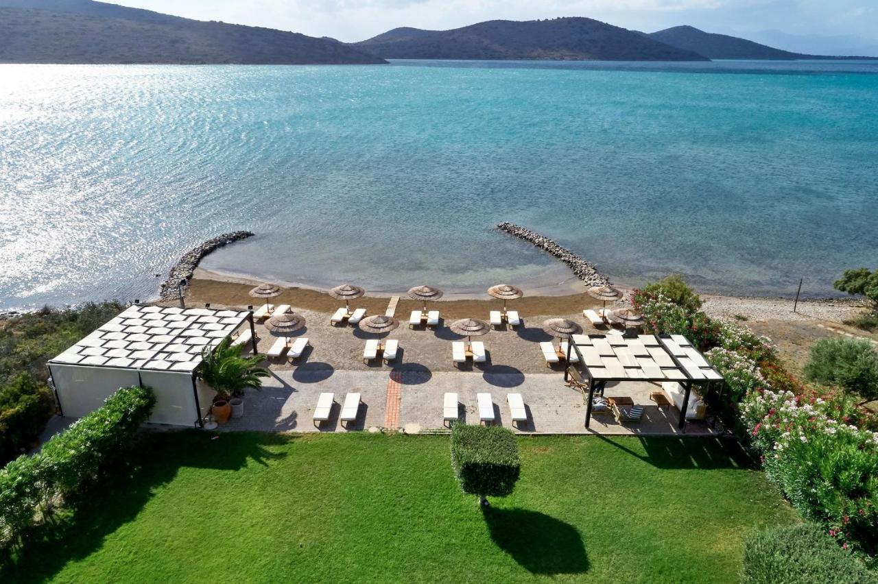 Een luchtfoto van een strand met stoelen en parasols. bij Elounda Gulf Villas by Sandglass in Elounda