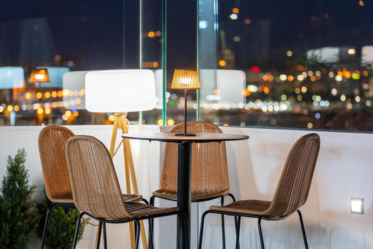 een tafel met drie stoelen en een tafel met een lamp bij Occidental Las Palmas in Las Palmas de Gran Canaria