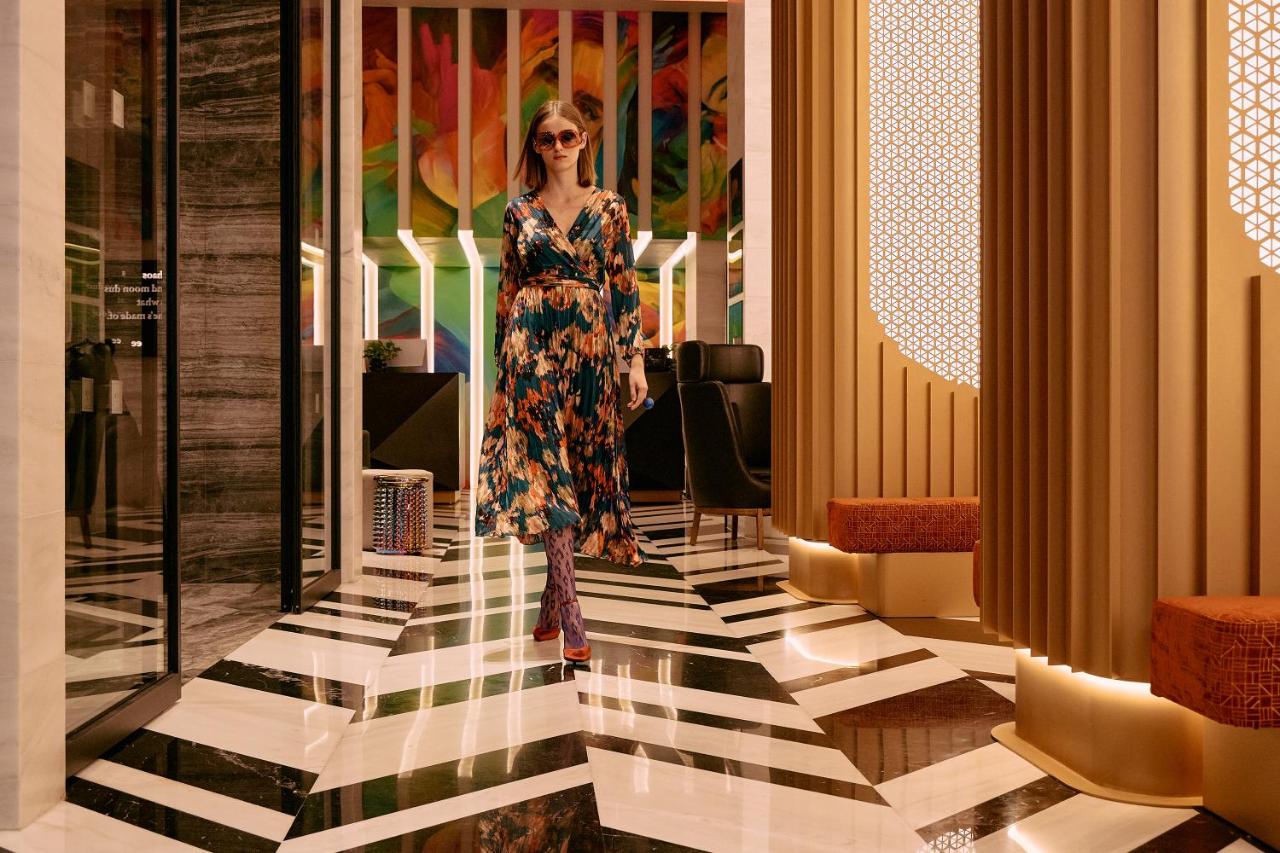 een vrouw in een jurk loopt door een gang bij NYX Esperia Palace Hotel Athens by Leonardo Hotels in Athene