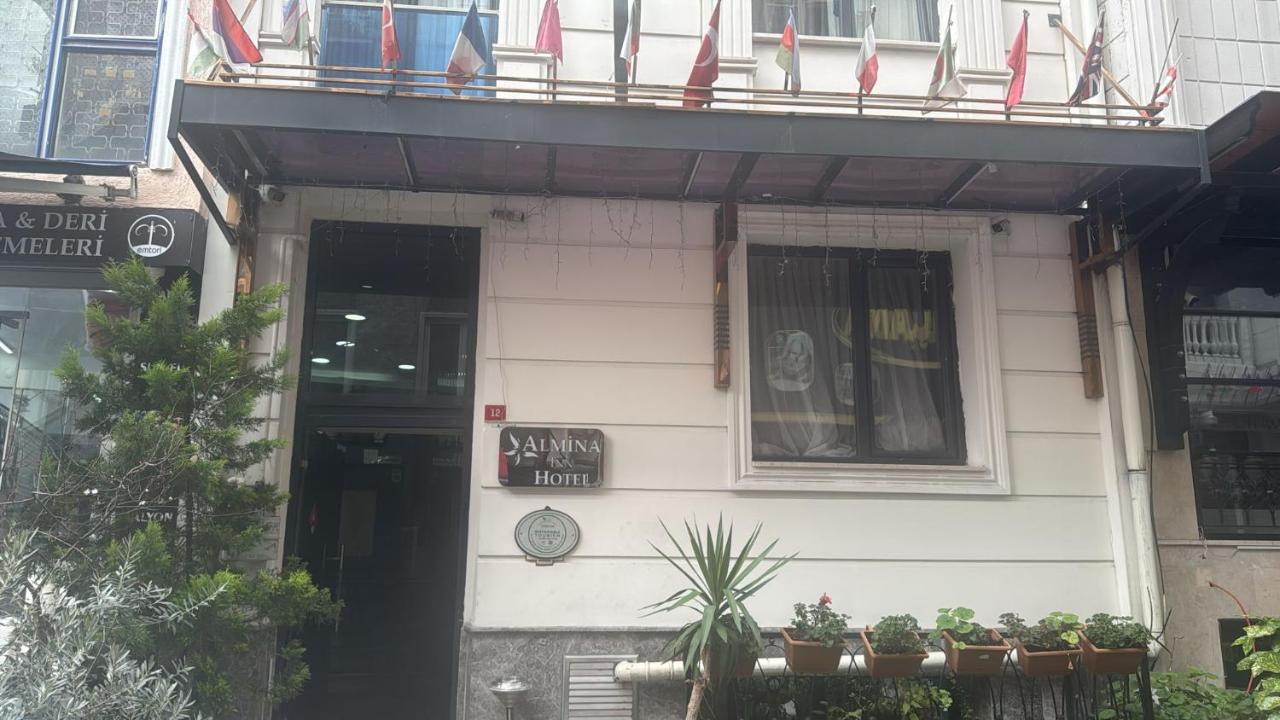 een wit gebouw met vlaggen op een balkon bij Hotel Almina İnn in Istanbul
