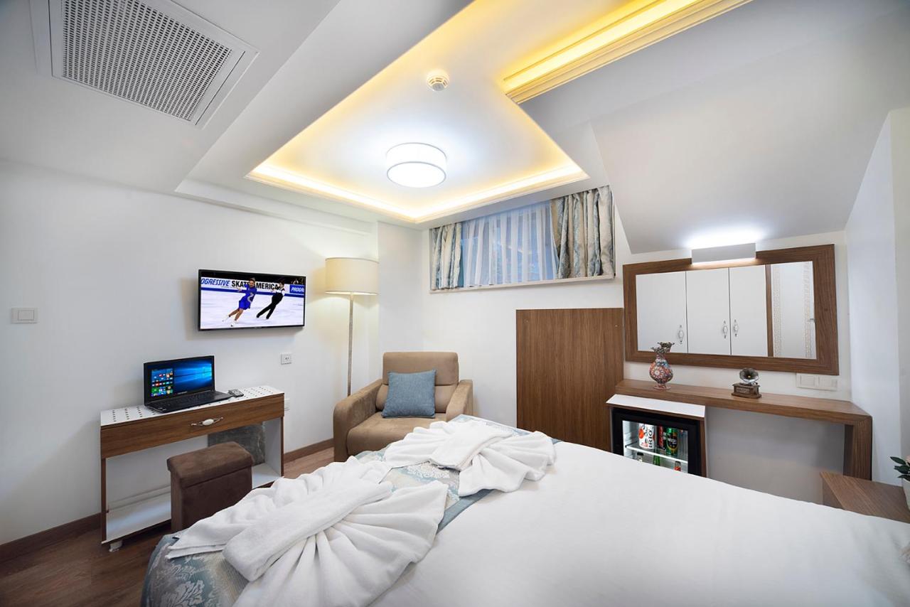 een slaapkamer met een bed, een bureau en een televisie bij Lika Hotel in Istanbul