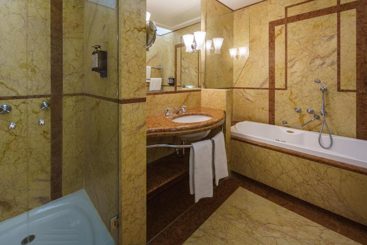 een badkamer met een wastafel en een badkuip en een wastafel bij Eurostars Hotel Excelsior in Napels