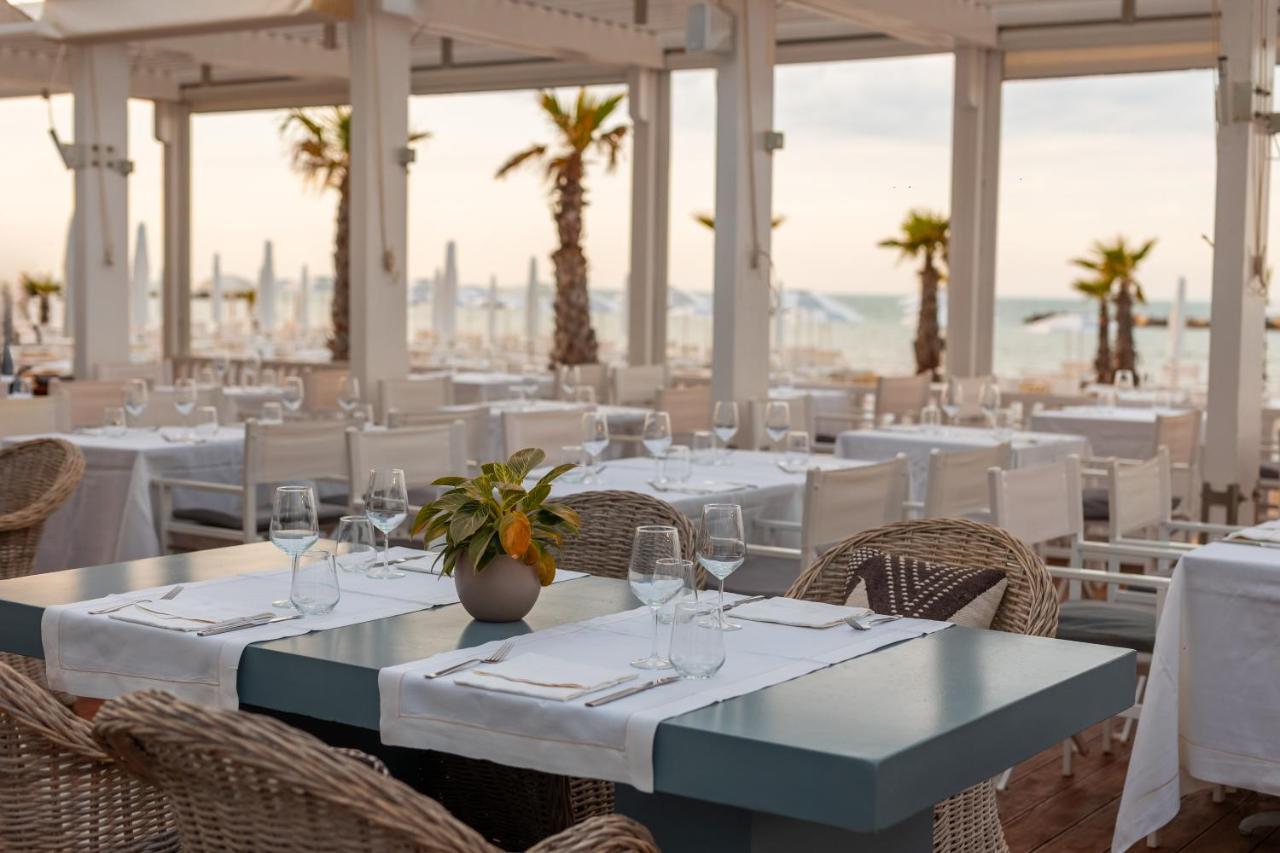 een restaurant met witte tafels en stoelen en palmbomen bij Excelsior Hotel, SPA & Lido - Preferred Hotels & Resorts in 