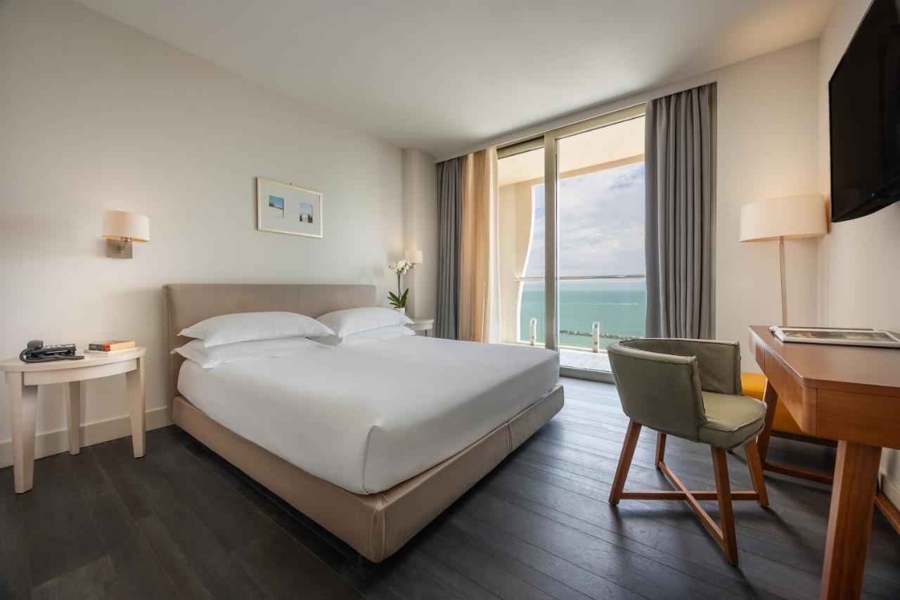 een hotelkamer met een bed, een bureau en een raam bij Excelsior Hotel, SPA & Lido - Preferred Hotels & Resorts in Pesar