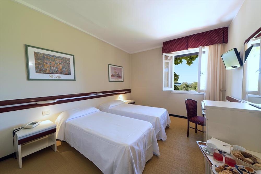 een hotelkamer met twee bedden en een raam bij Hotel Fabricia in Portoferraio +248 foto's