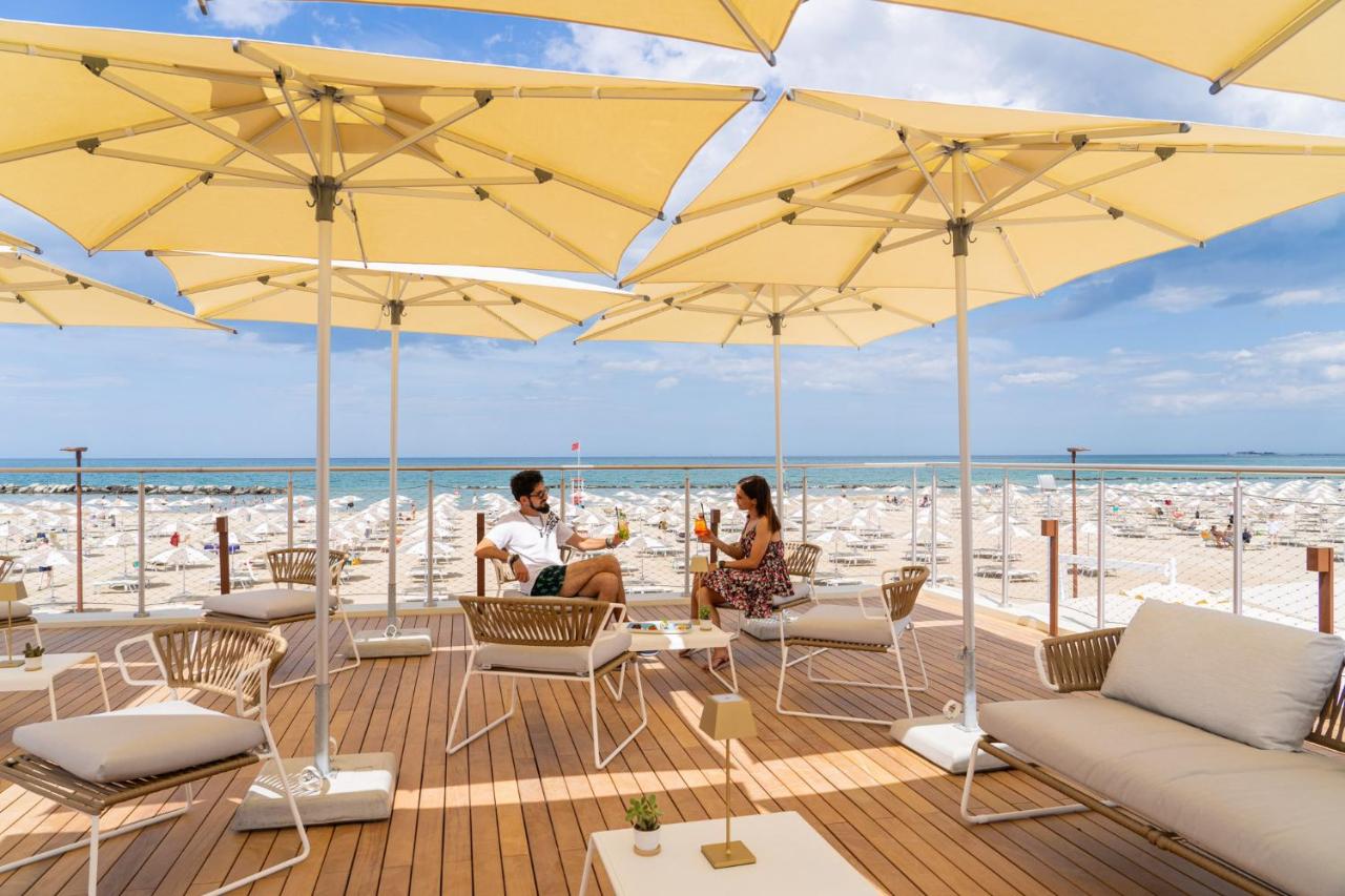 Twee mensen zitten onder parasols op het strand. bij Club del Sole Rimini Family Resort in Rimini