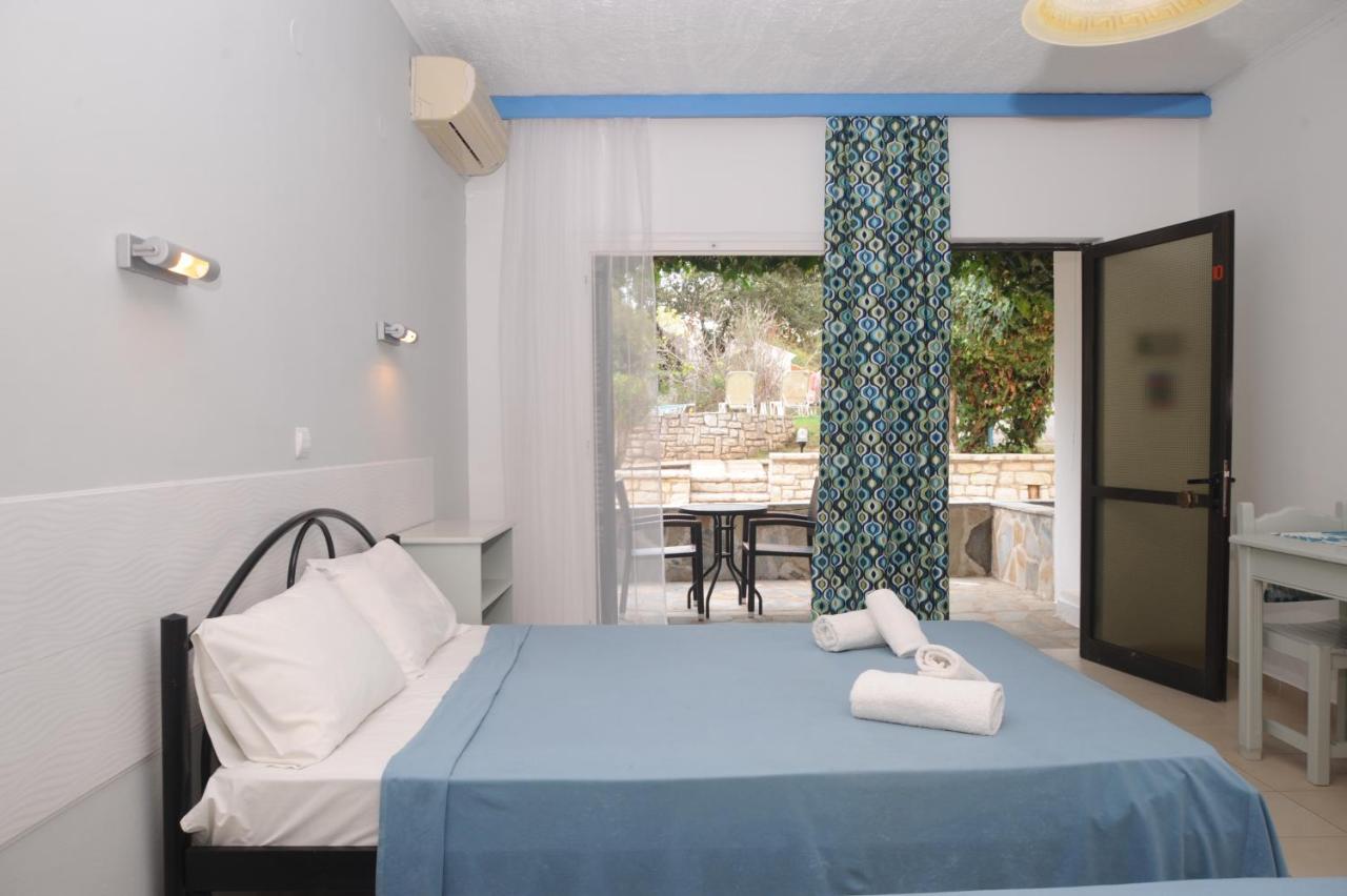 een slaapkamer met een bed met blauwe lakens en een raam bij Katia Beach Hotel in Kassiopi