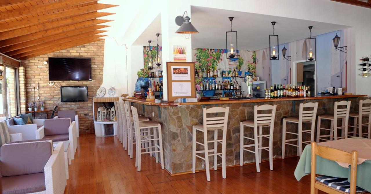 een bar in een restaurant met witte barkrukken bij Katia Beach Hotel in Kassiopi