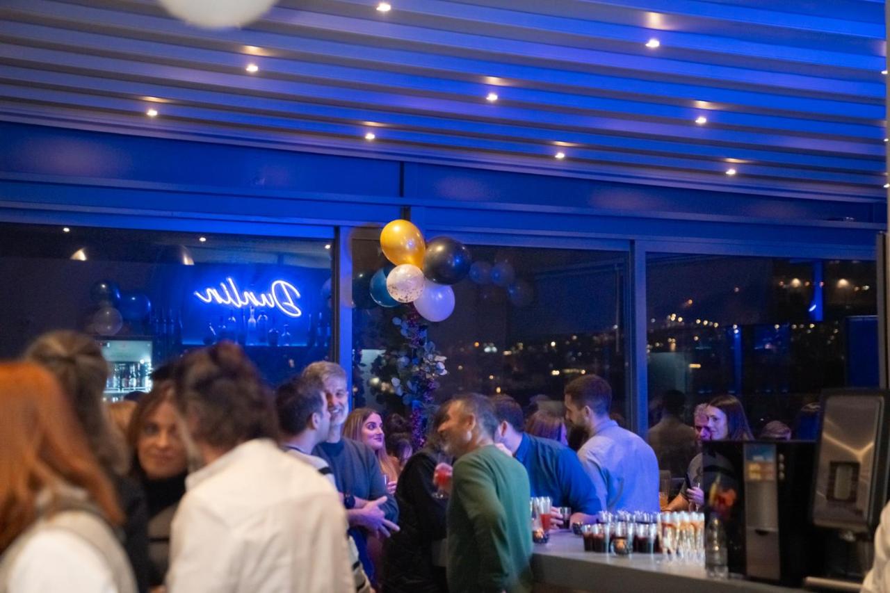een groep mensen die met ballonnen aan een bar staan bij Dunlin Hotel in Athene
