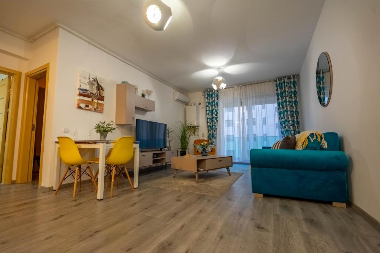een woonkamer met een blauwe bank en gele stoelen bij Sunny View Suites Mamaia by Moonlight Apartments in Mamaia