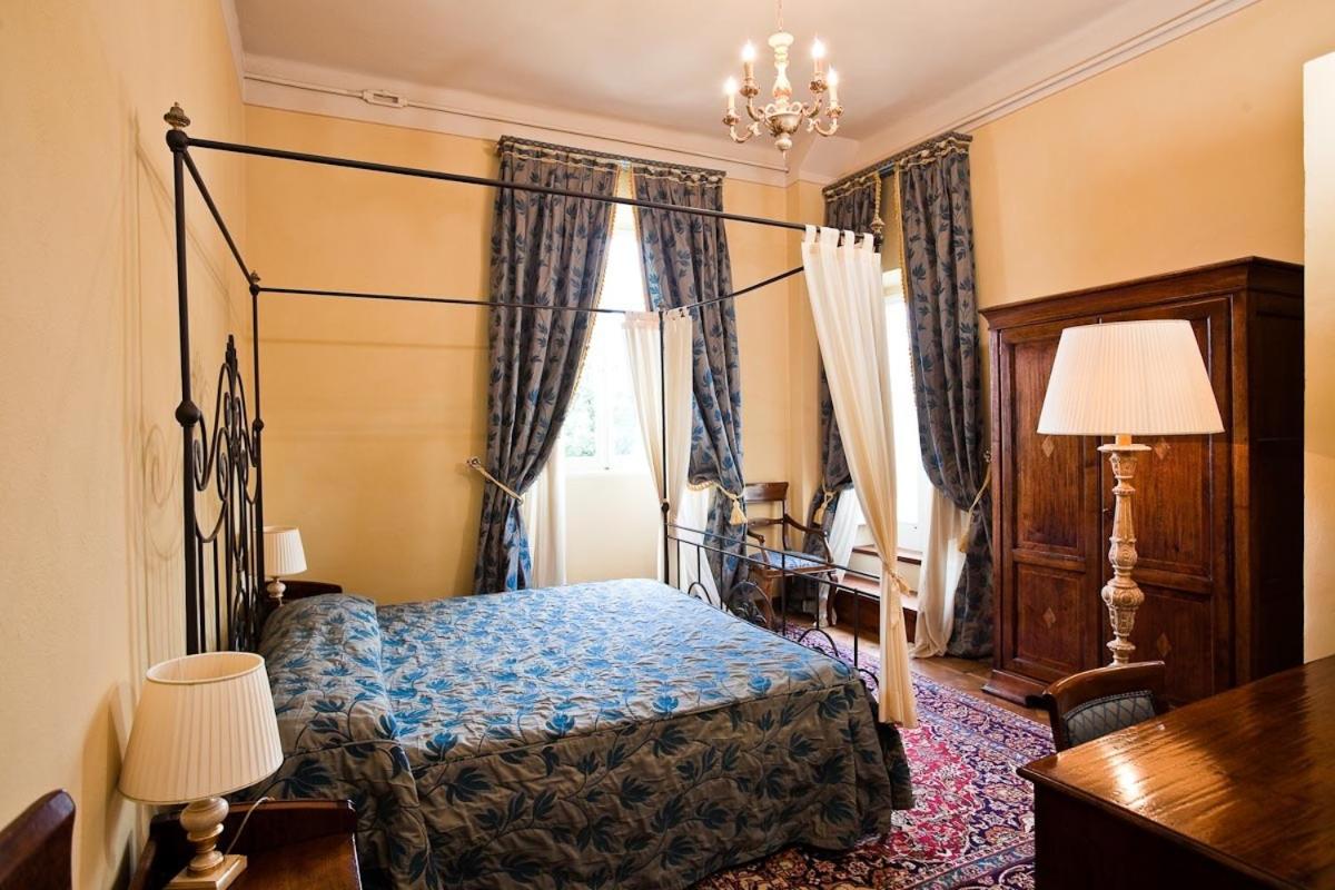 een slaapkamer met een bed, een bureau en gordijnen bij Castello Montegiove in Fano