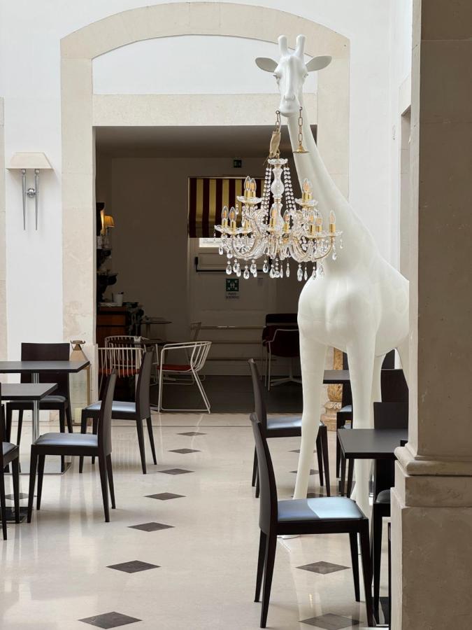 een beeld van een giraffe zittend op stoelen in een restaurant bij Hotel Palazzo Cavalieri in Siracusa