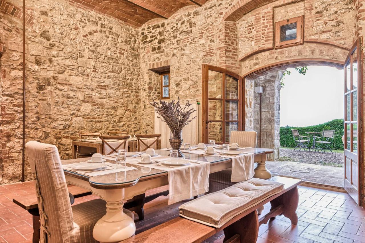 een eetkamer met een tafel en een stenen muur bij Borgo Di Pietrafitta Relais in Castellina in Chianti