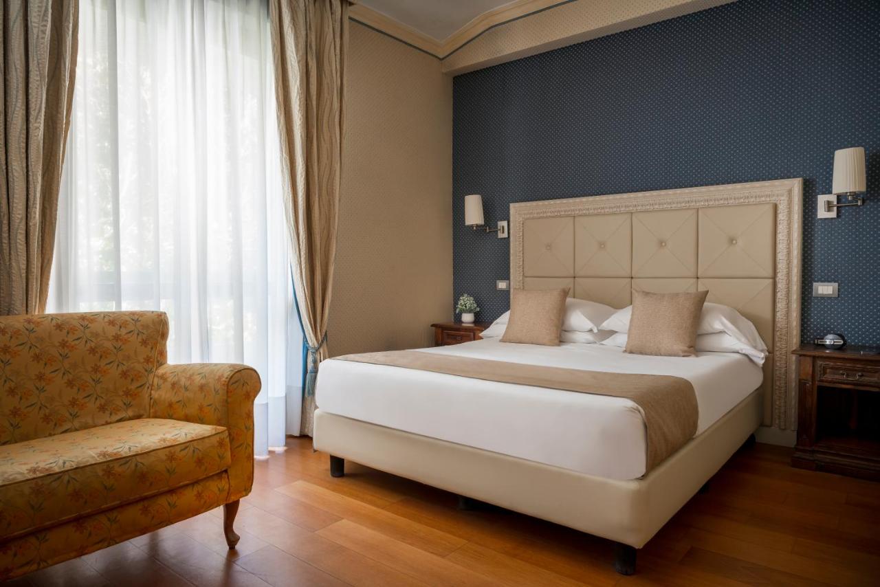 een slaapkamer met een groot bed en een stoel bij Grand Hotel Terme & SPA - Chianciano in Chianciano Terme