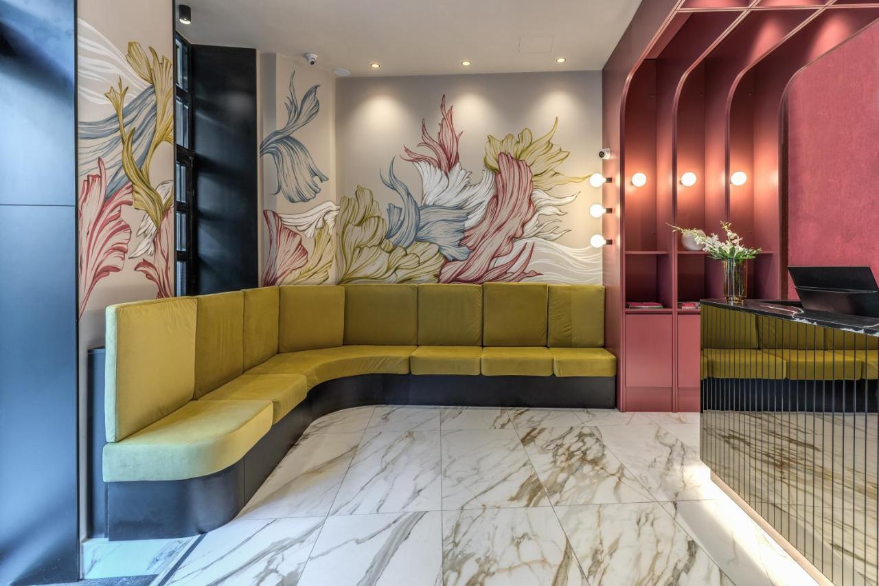 een lobby met een gele bank en een kleurrijke muurschildering bij Madison Hotel in Rome