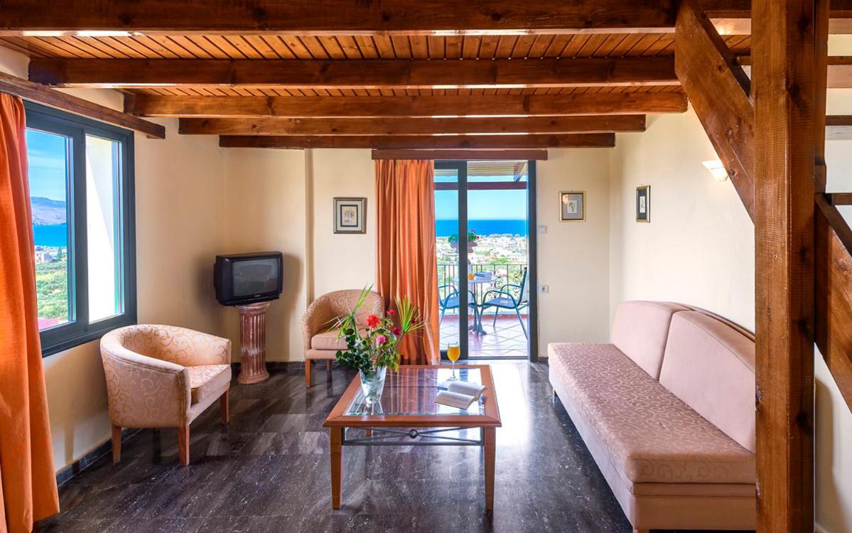 een woonkamer met een bank, stoelen en een tv bij Antilia Apartments in Tavronitis