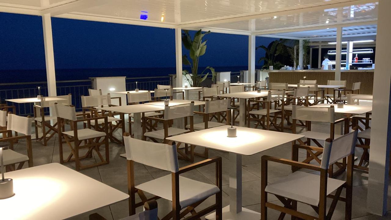 een kamer gevuld met tafels en stoelen met de oceaan op de achtergrond bij Punta Campanella Resort & Spa in Massa Lubren