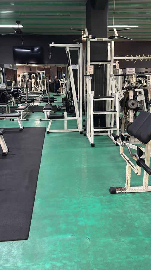 een sportschool met een groene vloer en een sportschool met fitnessapparaten bij CDH Hotel La Spezia in La Spezia