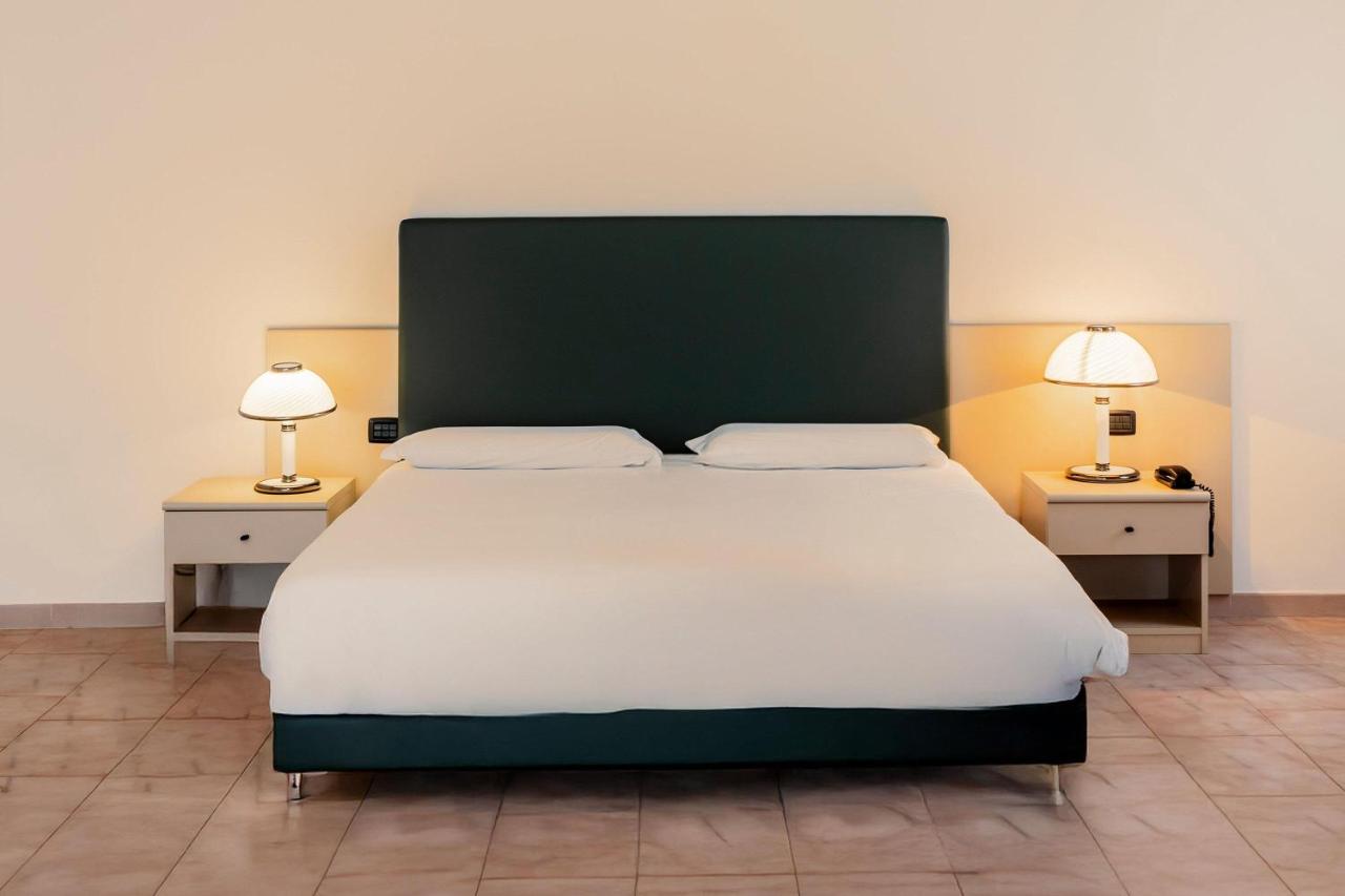 een slaapkamer met een groot bed en twee nachtkastjes bij B&B HOTEL Bari Rondò in Bari