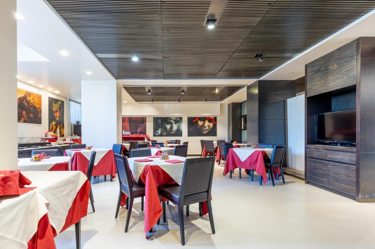 een restaurant met tafels en stoelen en een flatscreen-tv bij Wall Art Hotel & Residence in Prato