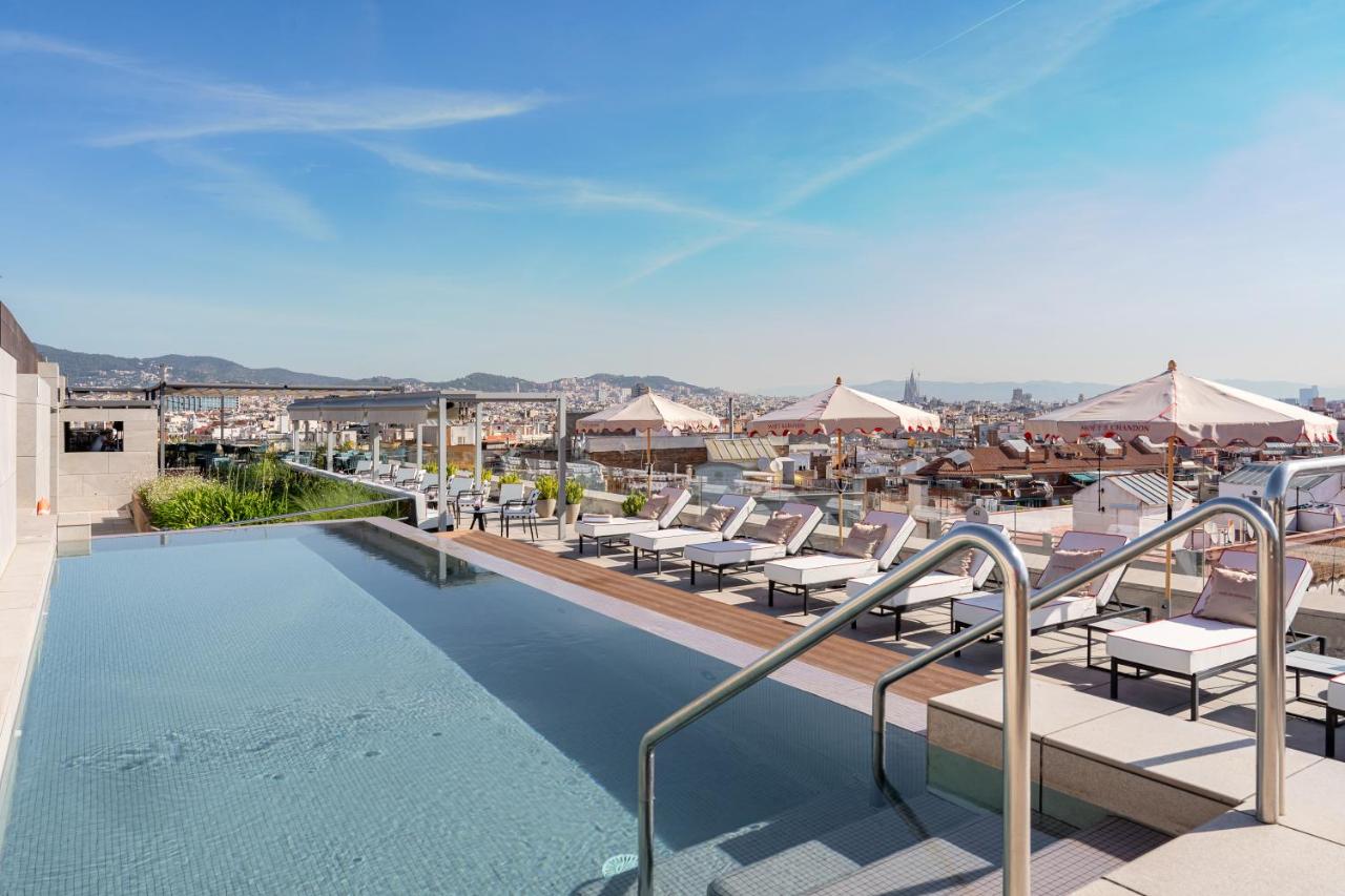 een zwembad met ligstoelen en parasols bij InterContinental Barcelona by IHG in Barcelona