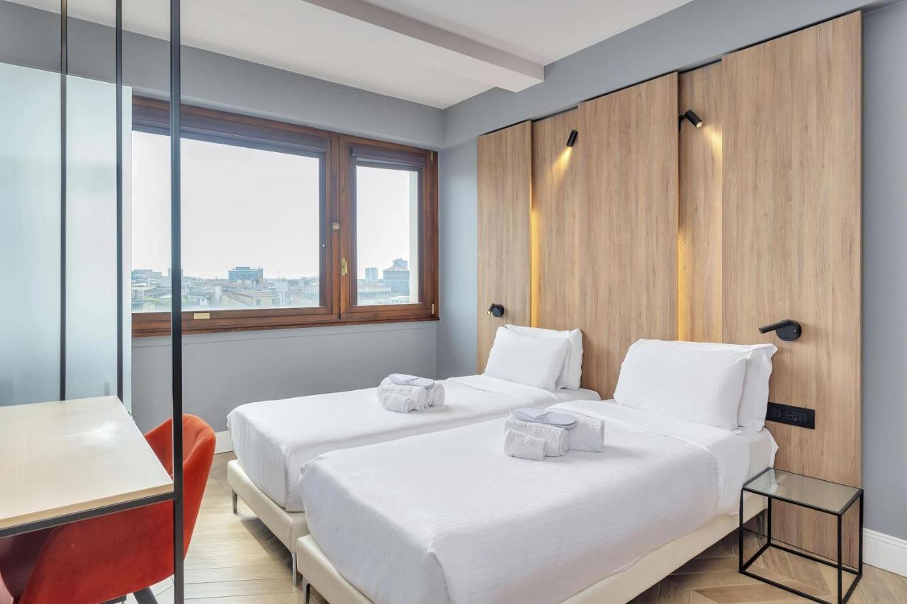 Twee bedden in een kamer met een bureau en een raam. bij B&B Hotel Milano City Center Duomo in Milaan