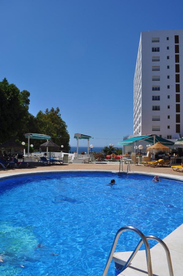 een groot blauw zwembad met een gebouw op de achtergrond bij First Flatotel International in Benalmádena