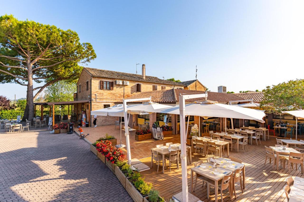 een terras met tafels en parasols voor een gebouw bij Club del Sole La Risacca Family Collection in Porto SantʼElpidio
