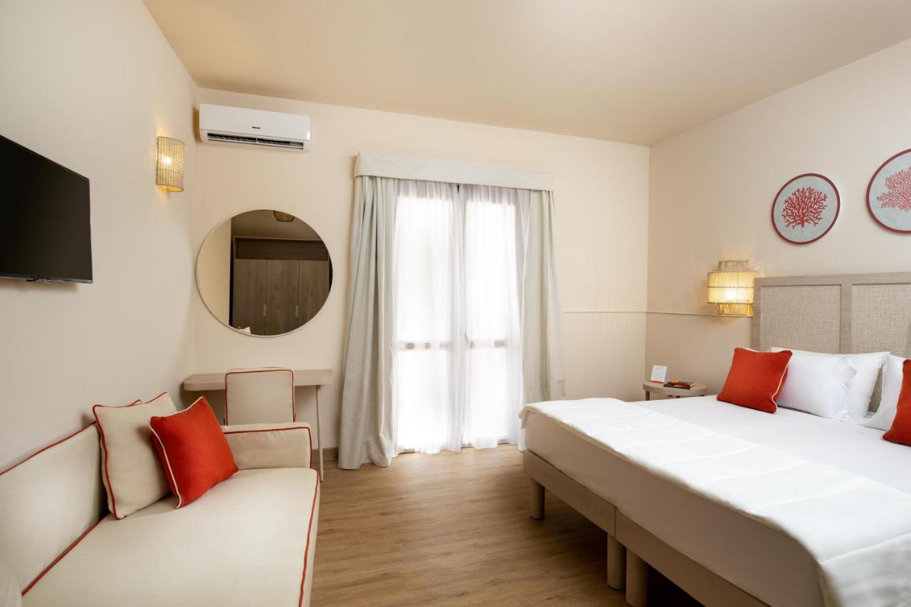 een hotelkamer met een groot bed en een bank bij VOI Le Muse Essentia in Zambrone