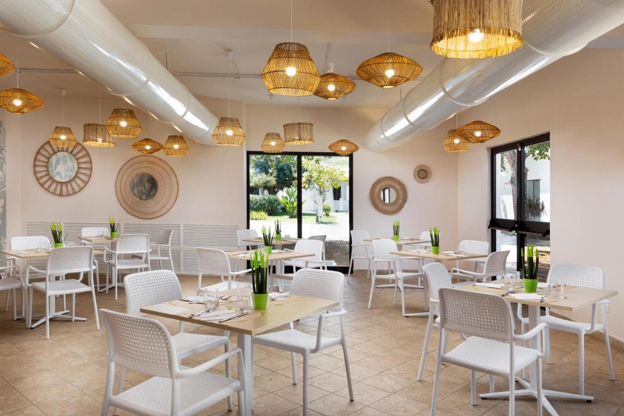 een eetkamer met tafels, stoelen en kroonluchters bij VOI Le Muse Essentia in Zambrone
