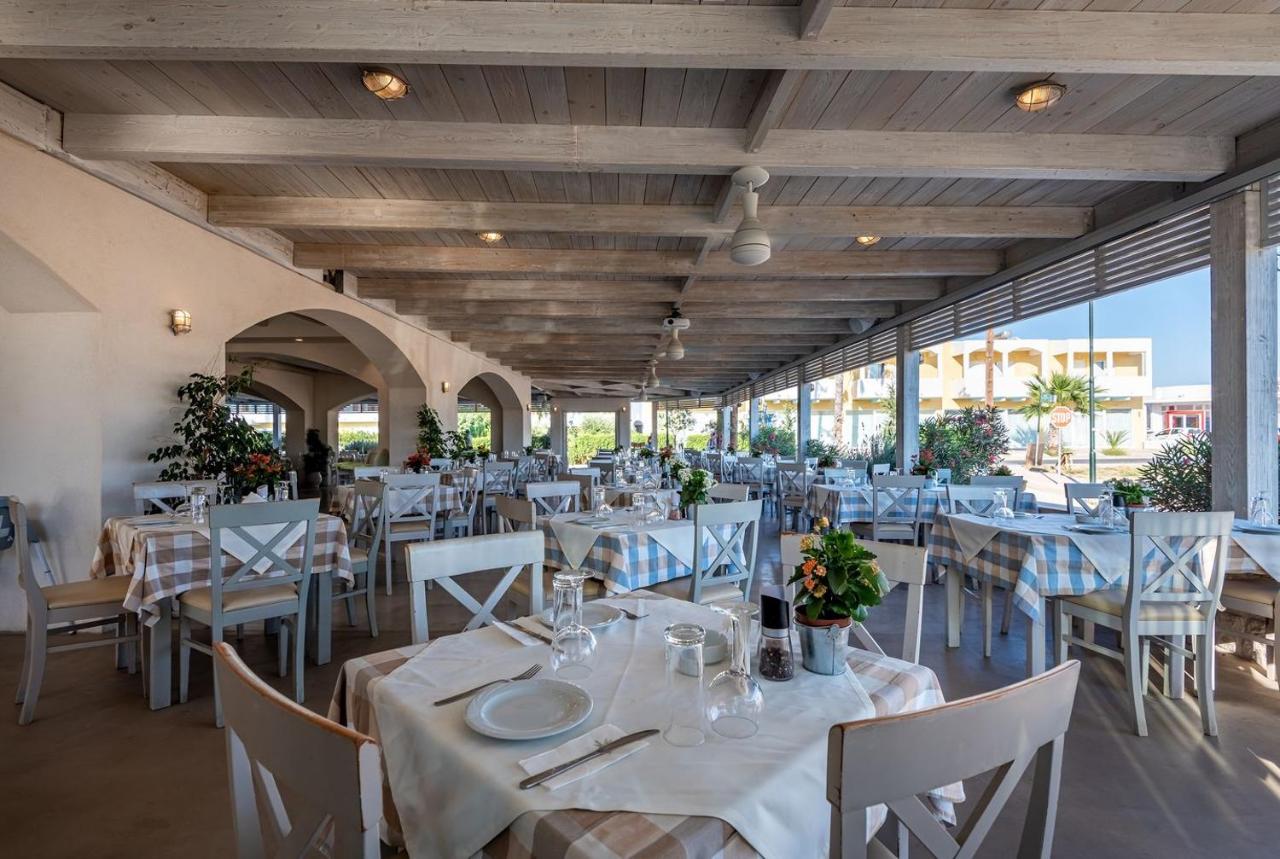 een restaurant met witte tafels en witte stoelen en tafelzoeker bij ONEIRO Boutique Hotel in Tigaki