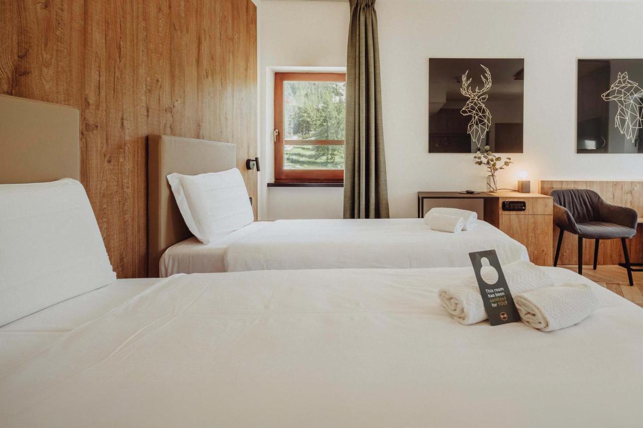 een hotelkamer met twee bedden en een raam bij B&B Hotel Passo Tre Croci Cortina in Cortina dʼAmpezzo