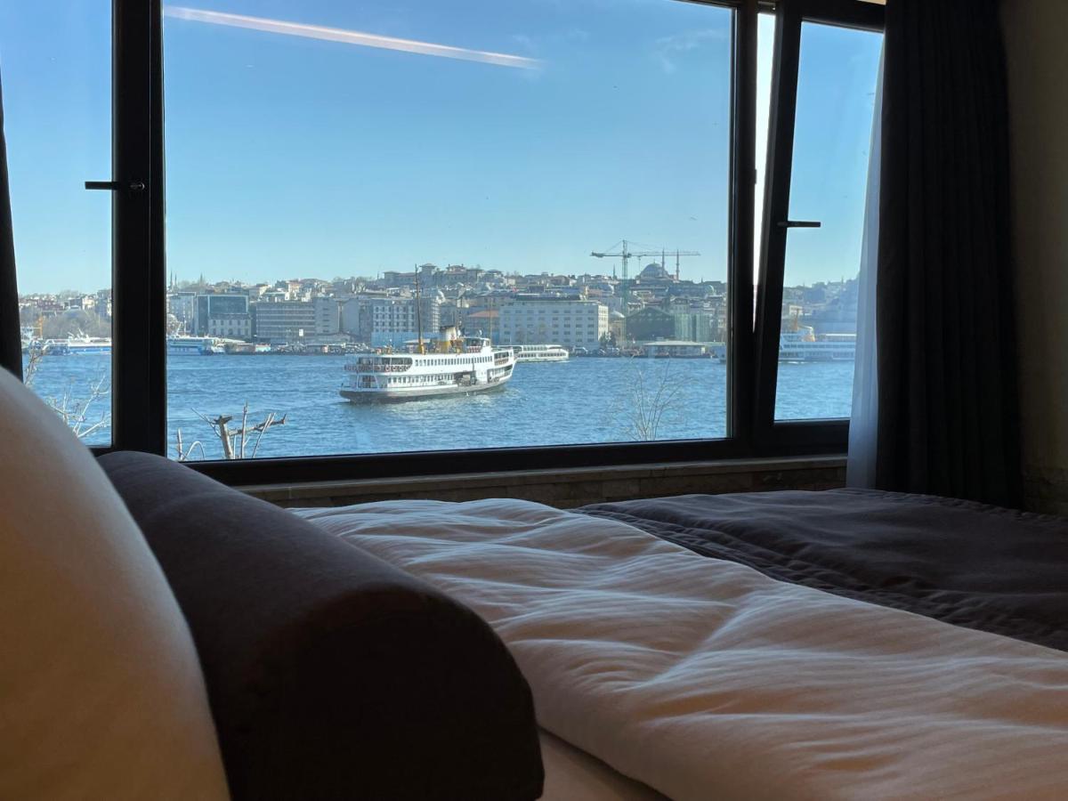 een slaapkamer met een groot raam met uitzicht op een boot in het water bij Weingart Seaside Hotel in Istanbul