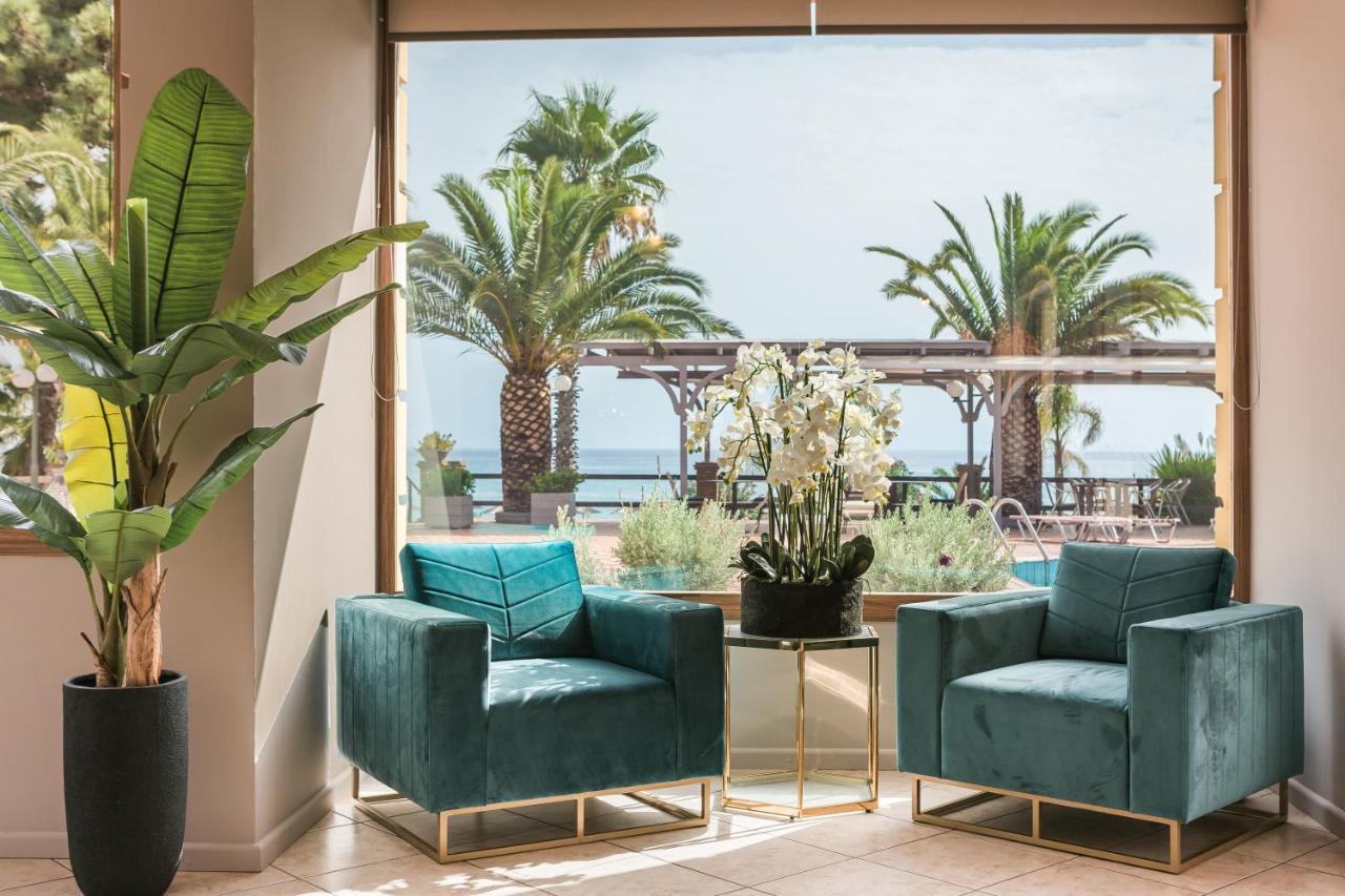 een lobby met twee blauwe stoelen en palmbomen bij Makis Hotel in Skála Kefalonias