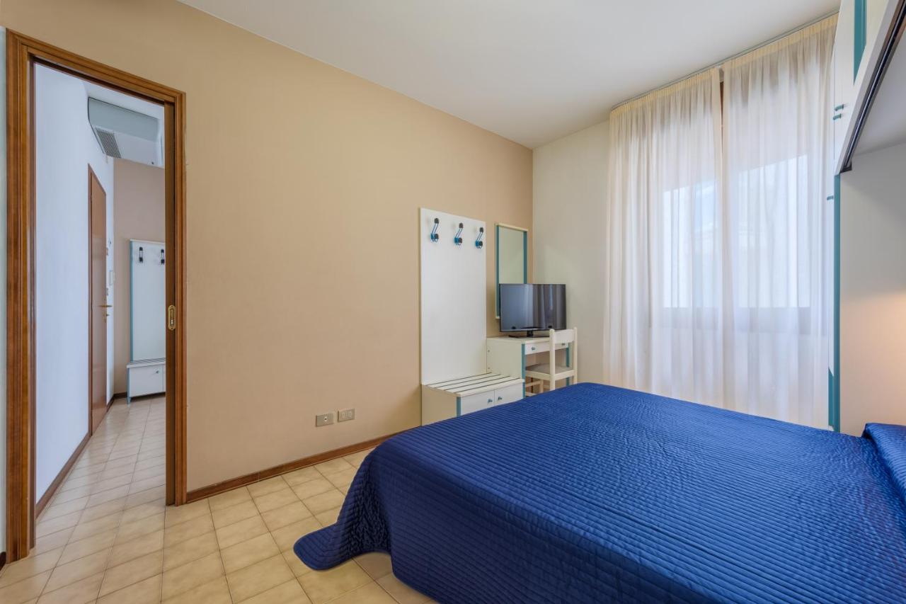 een slaapkamer met een blauw bed en een spiegel bij Hotel Sanremo in Lido di Jesolo +39 foto's