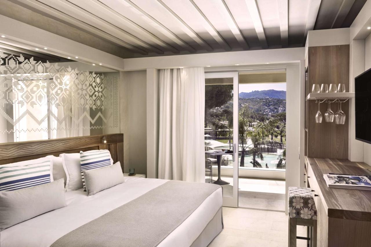 een slaapkamer met een groot bed en een balkon bij 7Pines Resort Sardinia - A Destination By Hyatt in Baja Sardinia