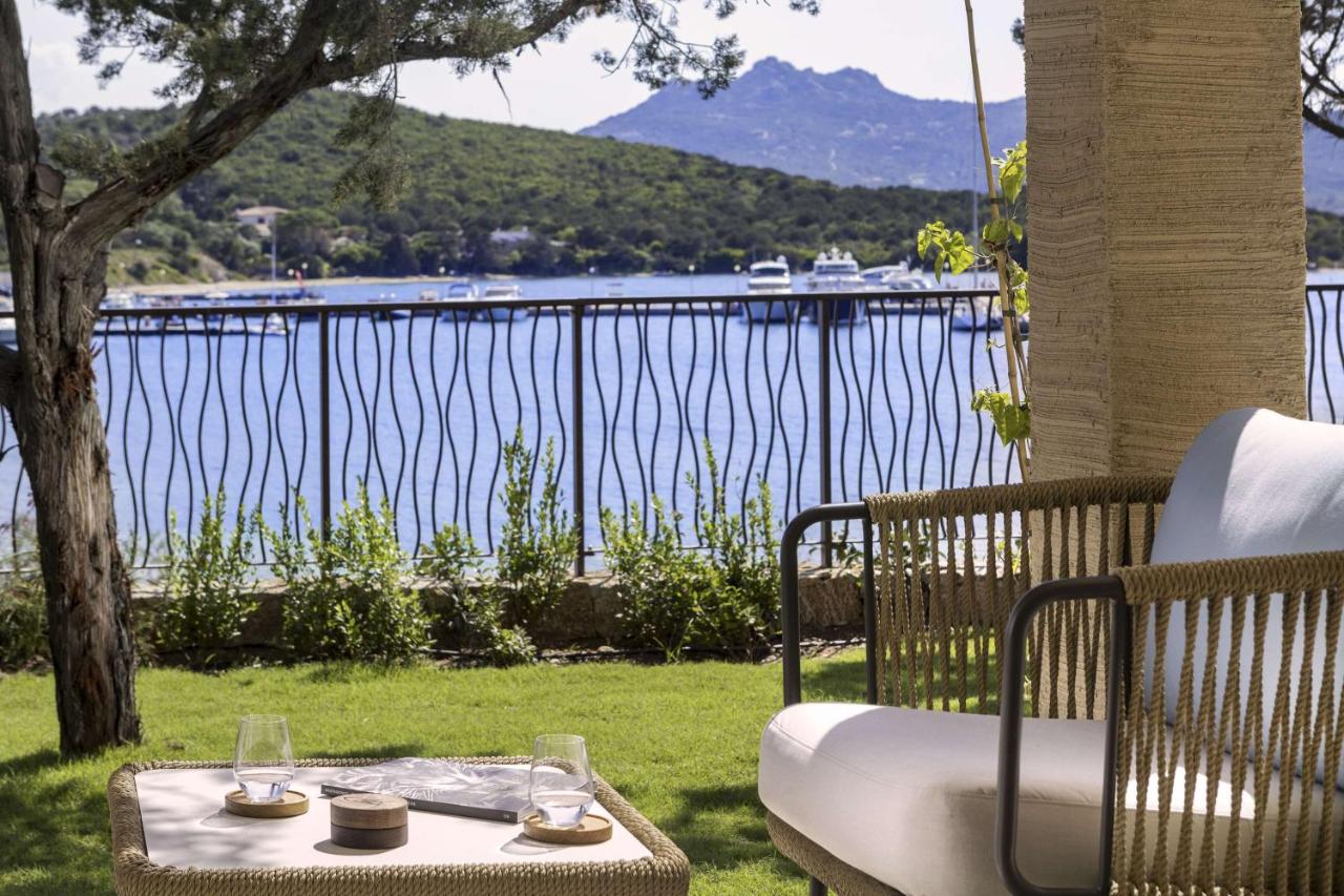 een tafel en een bank met uitzicht op het water bij 7Pines Resort Sardinia - A Destination By Hyatt in Baja Sardinia