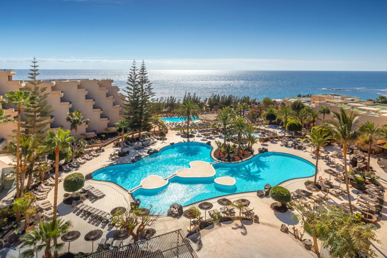Een luchtfoto van een resort met een zwembad en uitzicht op de oceaan. bij Barceló Lanzarote Royal Level in Costa Teguis