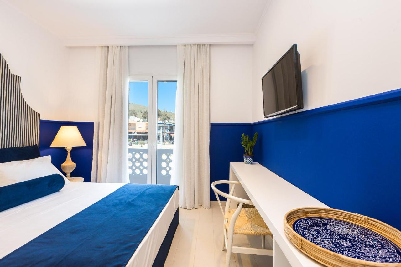 een blauw-witte slaapkamer met een bed en een tv. bij Georgioupolis Plaza Suites in Georgioupolis