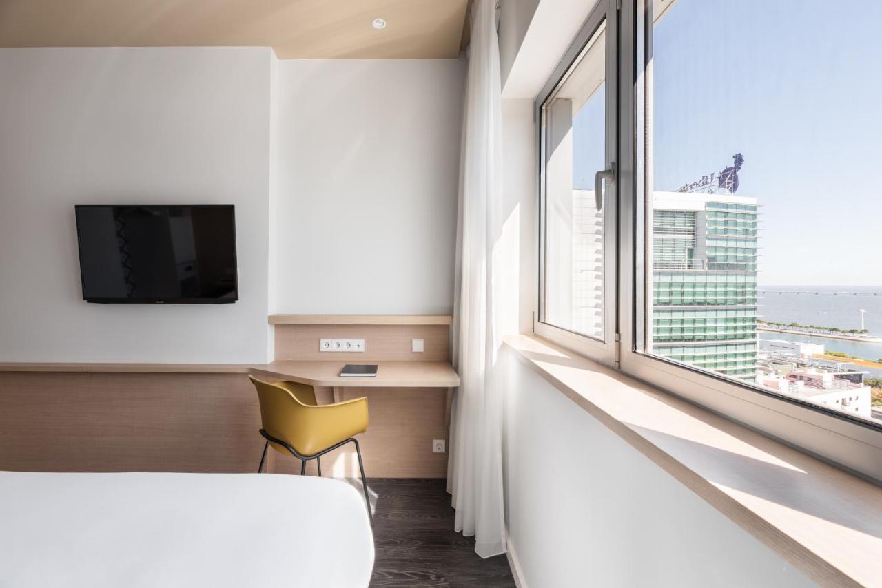 een slaapkamer met een groot raam en een gele stoel bij Ikonik Lisboa in Lissabon
