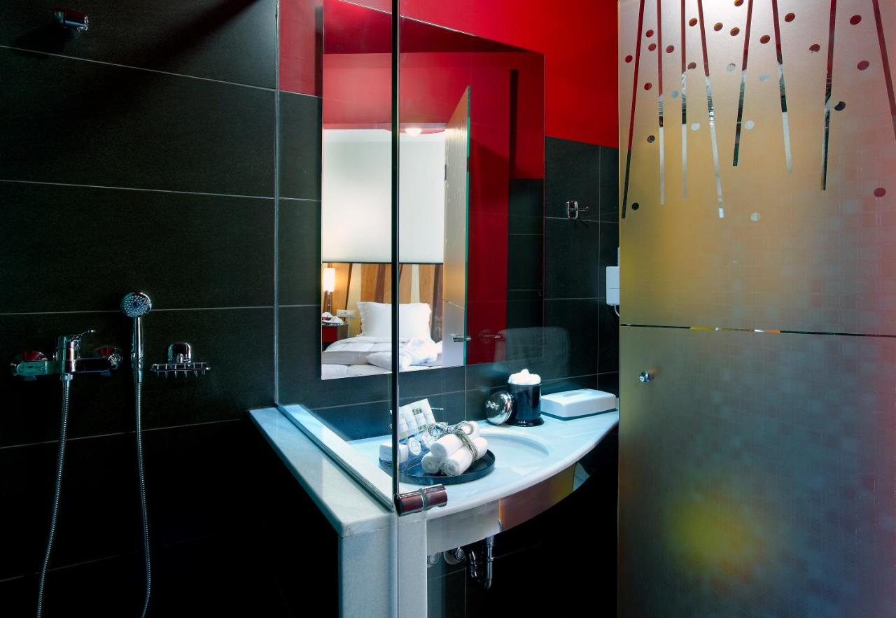 een badkamer met een wastafel, een spiegel en een koelkast bij Lato Annex Boutique Rooms in Heraklion