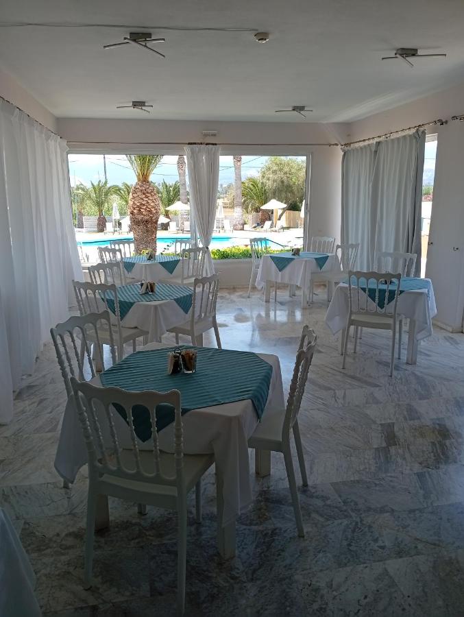 een eetkamer met tafels en stoelen en een zwembad bij Leonidas Hotel & Studios in Kos-stad