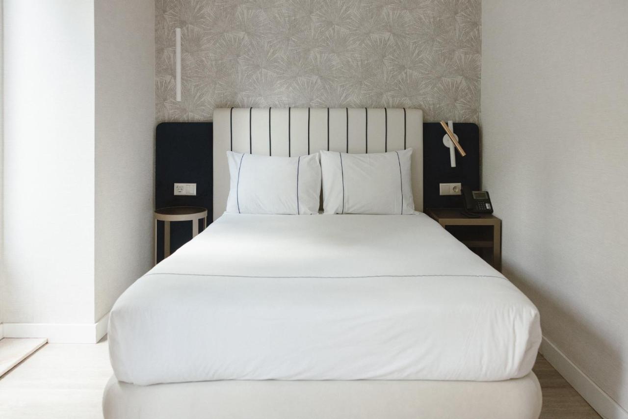 een slaapkamer met een groot bed met witte lakens en kussens bij M'AR De AR Auria in Lissabon