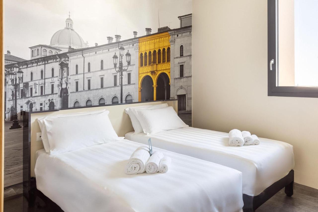 twee bedden met witte slippers erop in een kamer bij B&B Hotel Brescia in Brescia
