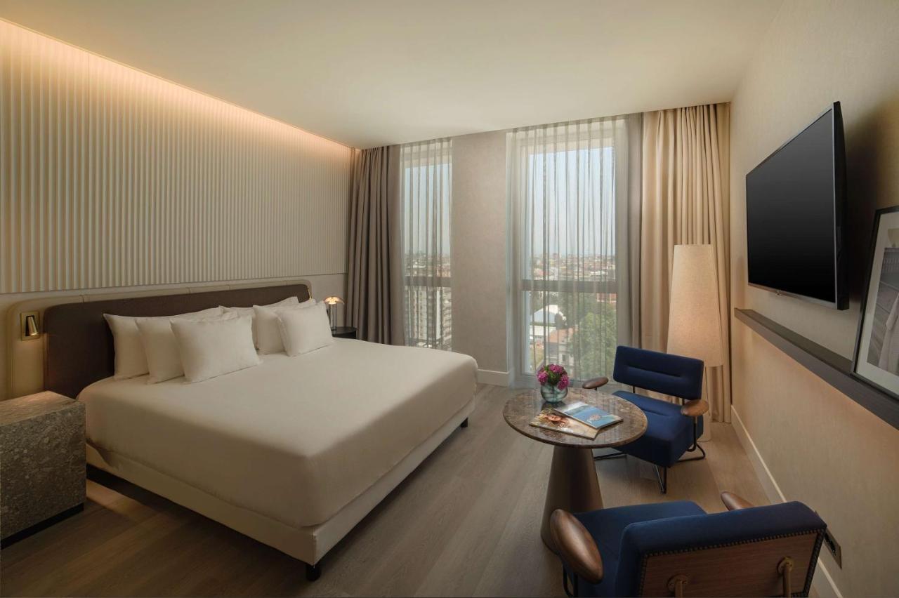 een hotelkamer met een bed, een tafel en een tv bij NH Collection Milano CityLife in Milaan