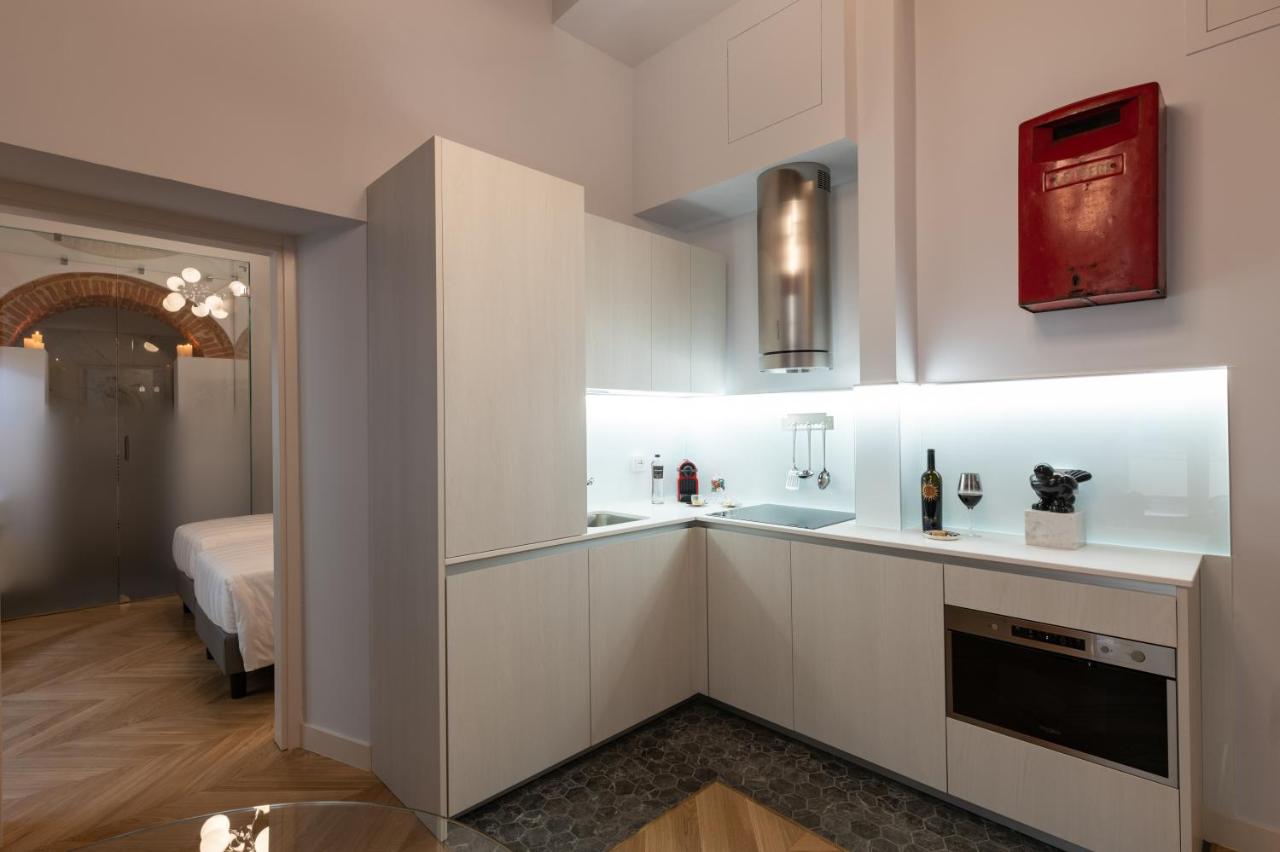 een keuken met witte kasten en een kamer met een bed bij Kairos by Florence Art Apartments in Florence
