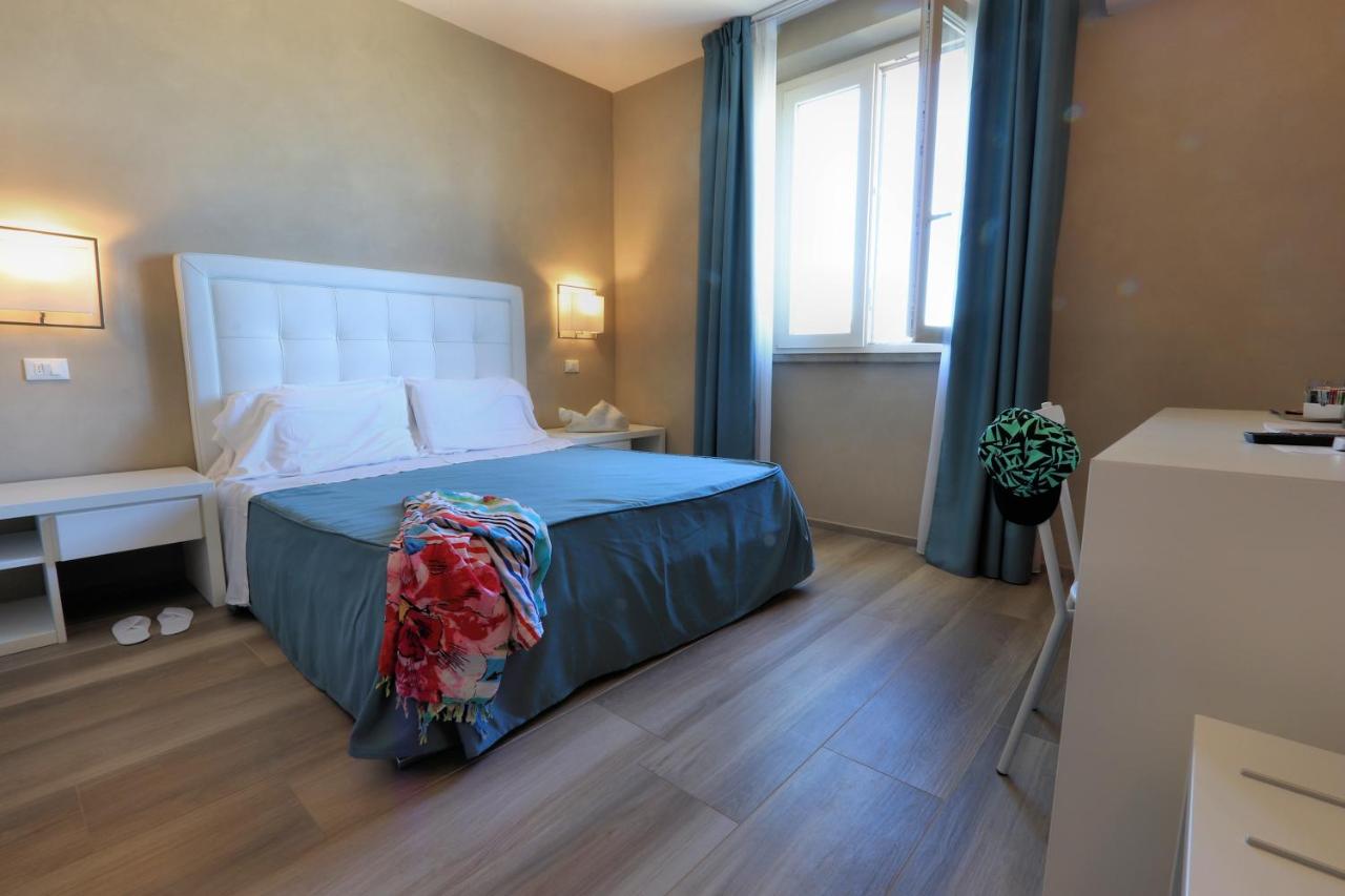 een slaapkamer met een bed met blauwe lakens en een raam bij Hotel Cecina Beach in Marina di Cecina