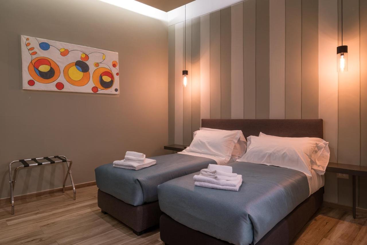 een slaapkamer met twee bedden en een schilderij aan de muur bij GOGO` Petit Hotel in Florence