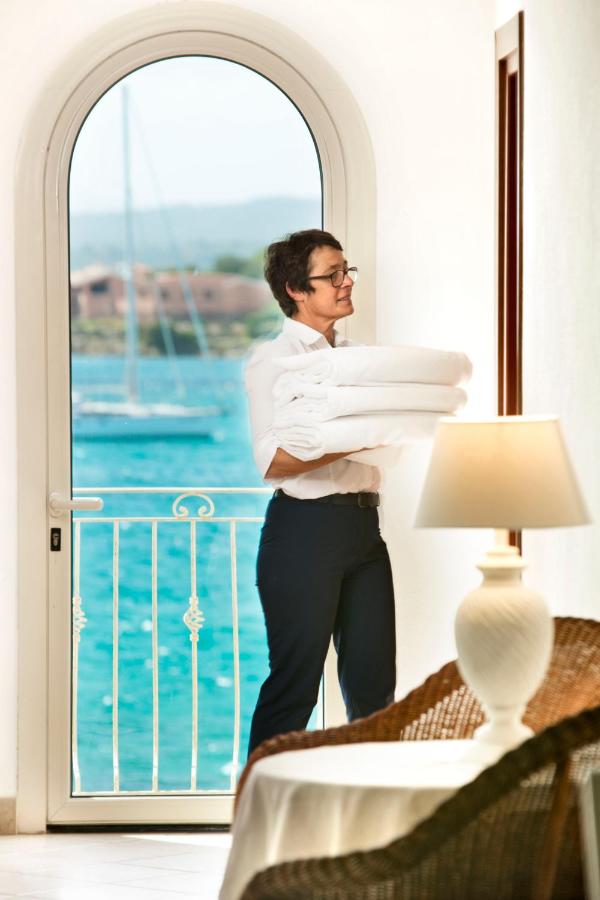 Een man staat voor een raam met een stapel borden in zijn handen. bij Gabbiano Azzurro Hotel & Suites in Golfo Aranci