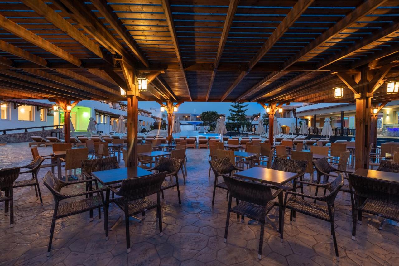 een restaurant met tafels, stoelen en verlichting bij Gaia Village in Tigaki